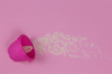 Bright pink baking cup lying sideways on the pink background sprinkled with sesame.