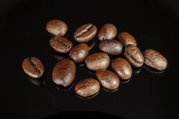 Fototapeta premium Well roasted coffee beans on a black background closeup.