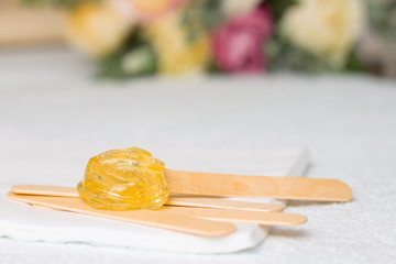 sugar paste or wax honey for hair removing with wooden waxing spatula sticks. flower background - depilation and beauty concept