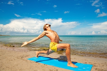 Fototapeta na wymiar athletic man on beach doing fitness yoga exercise. Acroyoga element for strength and balance.