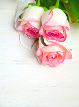 pink roses and lace on wooden white background 