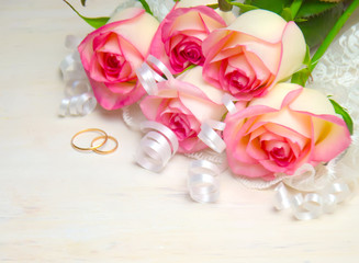 pink rose ribbon and wedding rings on wood white