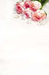 Obraz na płótnie Canvas pink rose ribbon and wedding rings on wood white 