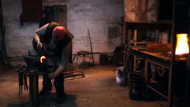 Hard men work. Blacksmith knocks with a hammer