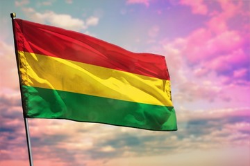 Fluttering Bolivia flag on colorful cloudy sky background. Prosperity concept.
