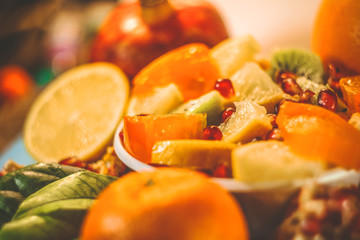 cut scitrus fruits. orange, pomegranate, mandarin, persimmon, kiwi. on a blue wooden board.