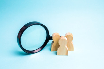Three wooden human figure stands near a magnifying glass on a blue background. Search for vacancies...