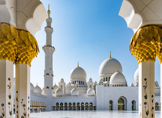 Sheikh Zayed Grand Mosque in Abu Dhabi seen between gold and marble pillars