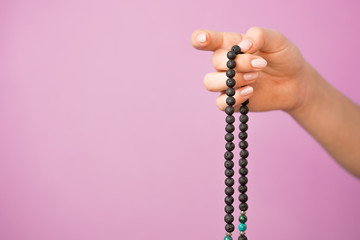 Woman, lit hand close up, counts Malas, strands of gemstones beads used for keeping count during...