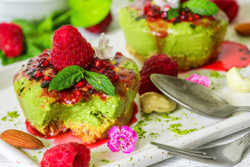 homemade raw matcha powder cakes with fresh berries, mint, nuts and eatable flowers with spoon. healthy vegan food