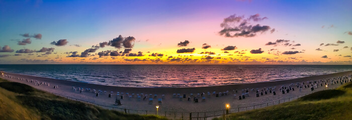 The beach of Westerland on the island of Sylt, Germany. Panoramic view at sundown with spectacular evening sky colors. - obrazy, fototapety, plakaty