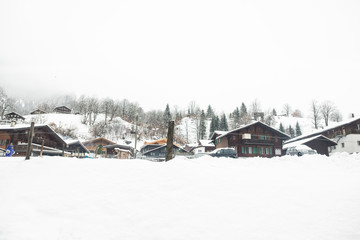 Fototapeta na wymiar Wooden houses covered in snow in mountain region of Lauterbrunen - switzerland.
