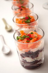 closeup of beet and salmon appetizers in little glasses on white background