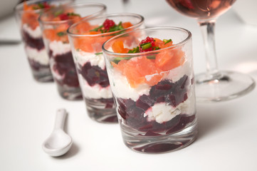 closeup of beet and salmon appetizers in little glasses on white background