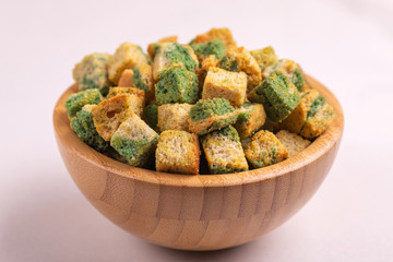 Spinach flavored crackers in wooden bowl on light marble background