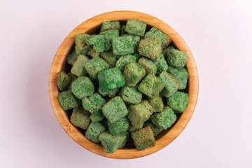 Wasabi flavored crackers in wooden bowl on light marble background