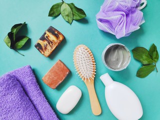 Flat lay spa organic beauty products for skin and hair care. Bathroom stuff. Purple terry towel, soap, shampoo, clay, sponge and comb - obrazy, fototapety, plakaty