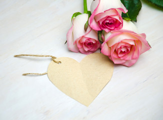 pink roses and tag, wooden heart on a white background 