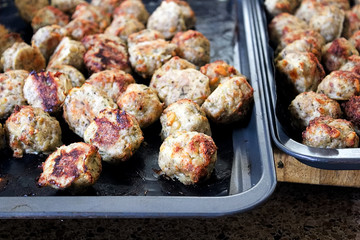 Freshly baked meatballs about to be taken off a cookie sheet