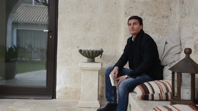 Giovane uomo legge un libro e si distrae al passaggio di una bella donna