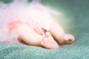 Baby ballerina in pink tutu. Soft focus of newborn feet.