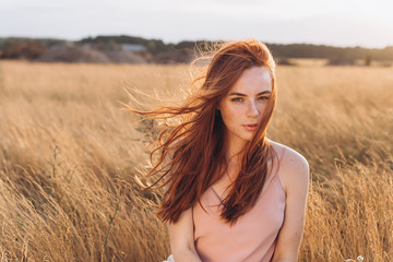 Outdoor portrait of young attractive ginger girl with freckles and lond hair. Natural beauty, casual, freedom concept