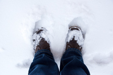 Feet in boots in the snow, top view