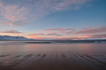 Landscape with a winter beach on the shore of the Barents Sea on the Kola Peninsula at sunset