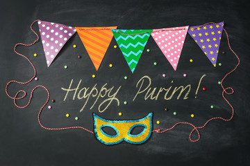 Carnival mask made of gold glitter, sparkles and inscription Happy Purim on chalkboard