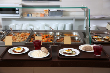 Trays with healthy food on serving line in school canteen