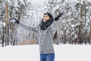 Fototapeta na wymiar Young beautiful brunette girl in a sweater in the winter snowy forest