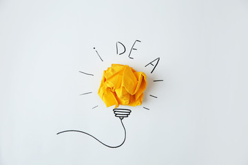 Composition with crumpled paper as lamp bulb and word IDEA on white background
