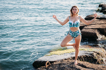 Girl doing yoga at beach, at sunset time. Healthy lifestyle.
