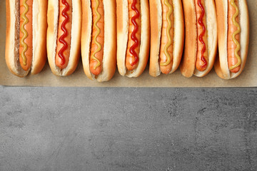 Tasty fresh hot dogs on grey background, top view. Space for text