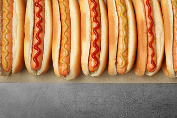 Tasty fresh hot dogs on grey background, top view