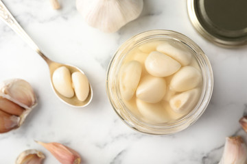 Preserved garlic in glass jar on table, top view. Space for text