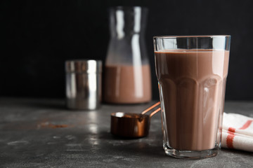 Glass with tasty chocolate milk on gray table, space for text. Dairy drink