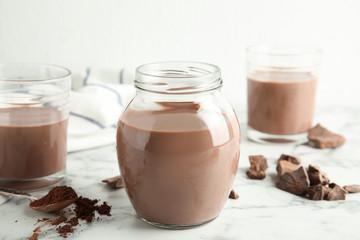 Glassware with tasty chocolate milk on marble table. Dairy drink