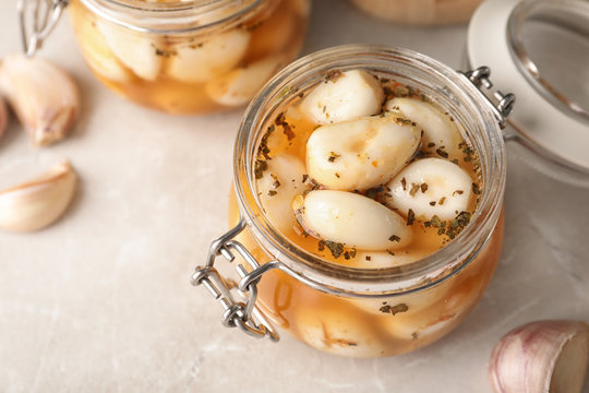 Preserved garlic in glass jar on table, closeup. Space for text