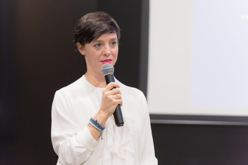 Beautiful business woman with microphone in her hand speaking at the  conference or seminar.