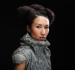 young Asian fashion model in grey dress against black background