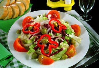 Plato con una ensalada de lechuga, tomate, pimiento, cebolla y aceitunas.