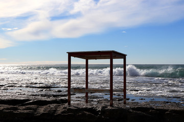 Table on a cliff with sea waves on background.