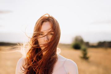 Outdoor portrait of young attractive ginger girl with freckles and lond hair. Natural beauty,...