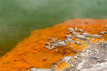 Closeup of the edge of the Champagne Pool at the Wai-O-Tapu geothermal area showing the orange...