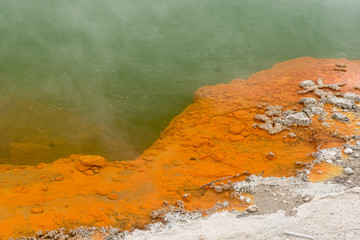 Closeup of the edge of the Champagne Pool at the Wai-O-Tapu geothermal area showing the orange...