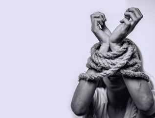  Concept of gender discrimination against women.  Hands tied up with rope of woman. Black and white portrait photo.