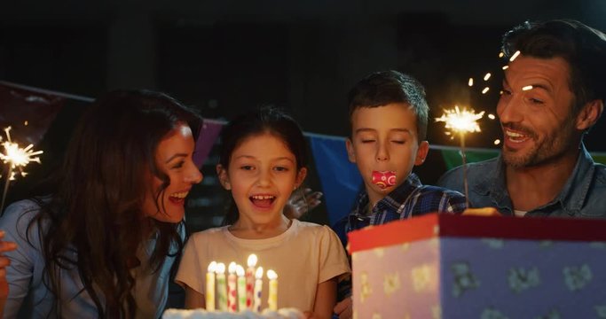 Portrait of happy family celebrating birthday of kid blowing a cake candles in slow motion. - Powered by Adobe