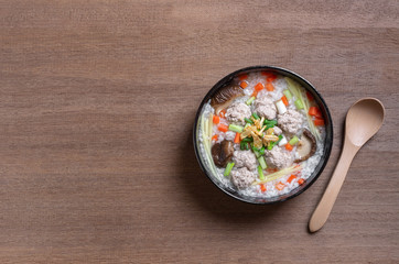 top view of boiled rice clear soup with pork in a ceramic bowl on wooden table. homemade style food concept.