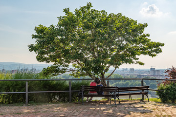 Obraz premium Novi Sad, Serbia - May 27, 2018: The couple in love is sitting on the bench at the Petrovaradin Fortress